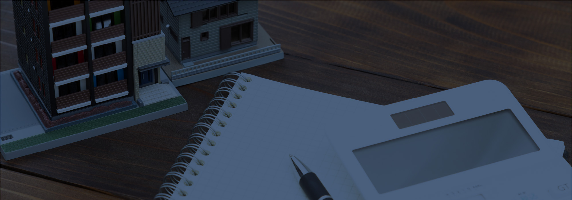 建物の模型とノート、ペンが置かれたデスクの写真